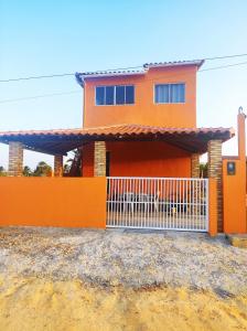 a orange house with a white gate in front of it at Chalé Sol de Verão Macapá-Pi in Luis Correia