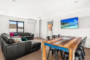 uma sala de estar com uma mesa e um sofá em Coast Leumeah em Surf Beach