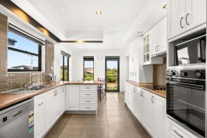 uma cozinha com armários brancos e uma grande janela em Coast Leumeah em Surf Beach