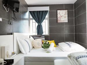 ein Zimmer mit einem Sofa mit Kissen und einem Fenster in der Unterkunft Joyous Guest House in Hongkong