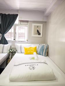 ein Schlafzimmer mit einem großen weißen Bett mit gelben Kissen in der Unterkunft Joyous Guest House in Hongkong