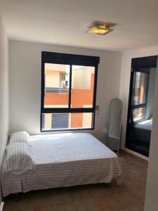 a bedroom with a bed and a large window at Adosado, wifi, playa, lugar espacioso, vacacional in Grao de Castellón