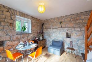 Habitación con mesa, sillas y pared de piedra. en House Honey, en Lovreć