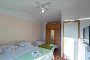 een slaapkamer met 2 bedden en een plafondventilator bij House Honey in Lovreć