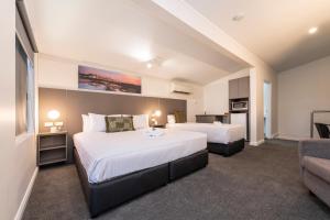 Habitación de hotel con 2 camas y sofá en Fern Bay Motel en Newcastle