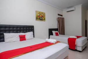 1 dormitorio con 2 camas y almohadas rojas y blancas en RedDoorz Syariah near RS Hermina Yogyakarta, en Seturan
