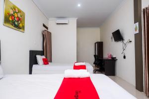 Habitación de hotel con 2 camas y manta roja en RedDoorz Syariah near RS Hermina Yogyakarta, en Seturan