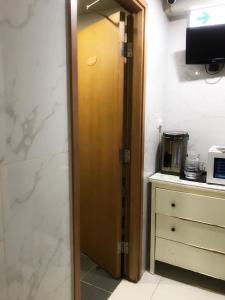 ein Bad mit einer Holztür in einem Zimmer in der Unterkunft Joyous Guest House in Hongkong