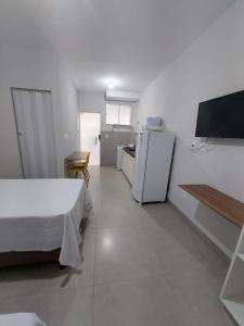 um quarto branco com uma cama e um frigorífico em FLAT SABIÁ em Uberlândia