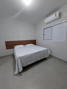 a white bedroom with a bed and a window at FLAT SABIÁ in Uberlândia