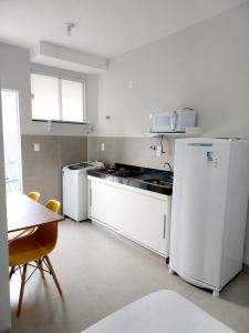 a kitchen with white appliances and a table with chairs at FLAT SABIÁ in Uberlândia