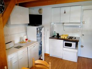 una pequeña cocina con armarios blancos y microondas en Appartement Mont-Dore, 2 pièces, 5 personnes - FR-1-415-113, en Le Mont-Dore