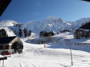 una montaña cubierta de nieve con un edificio y una pista de esquí en Appartement Mont-Dore, 2 pièces, 5 personnes - FR-1-415-113, en Le Mont-Dore