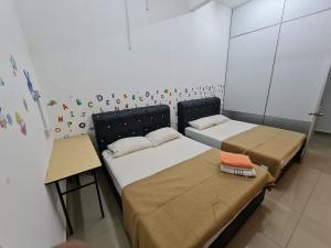 a room with two beds and a table in it at Roomstay Gemilang in Kuala Terengganu