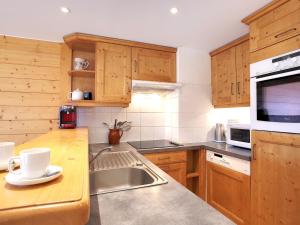 a kitchen with wooden cabinets and a stainless steel sink at Charmant Appartement à Courchevel avec Parking et Wifi, Pieds des Pistes, 6 Pers. - FR-1-575-158 in Courchevel