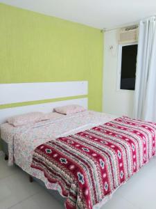 Un dormitorio con una cama con una manta. en Flat Praia de Icaraí, 2 qts, 1vaga garagem e piscina en Niterói