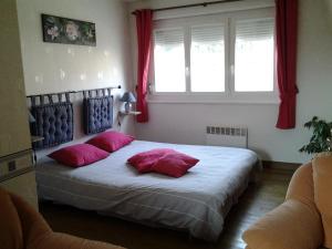 Un dormitorio con una cama con almohadas rosas y una ventana en Chambres d’hotes vue sur la Campagne, en Marquise