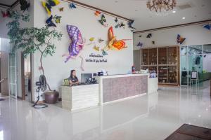 a woman sitting at a desk in a lobby with butterflies on the wall at Saline Hot Spring Resort นำ้พุร้อนเค็ม รีสอร์ท 