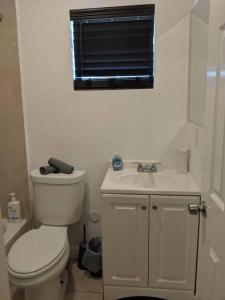 een witte badkamer met een toilet en een wastafel bij 3 Bedroom Miami Home 15 Minutes to the Beach in Miami