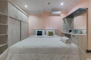 ein Schlafzimmer mit einem großen weißen Bett mit Kissen in der Unterkunft Urbanview Palace Syariah Balikpapan by RedDoorz in Balikpapan