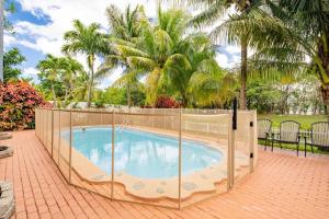 a fence around a swimming pool with palm trees at Waterfront 2-Story Villa with Heated Pool in Pembroke Pines