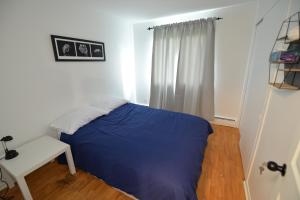 een slaapkamer met een blauw bed en een witte stoel bij Détente au bord de l'eau in Bécancour