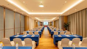 Holiday Inn Express Linyi Riverside, an IHG Hotel في ليني: قاعة المؤتمرات مع الطاولات الزرقاء والكراسي البيضاء