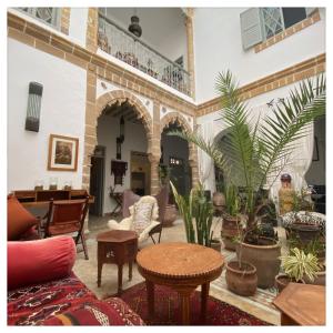 ein Wohnzimmer mit vielen Pflanzen und Tischen in der Unterkunft Riad le Consulat - Private Riad, Breakfast included in Essaouira