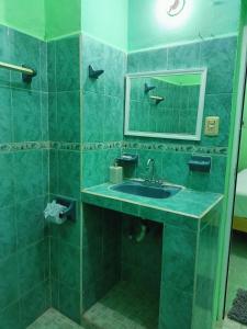 a green bathroom with a sink and a mirror at Casa Bonzay in Bacalar