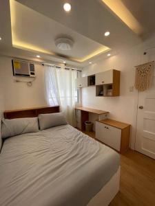 1 dormitorio con 1 cama blanca grande y escritorio en Casa Lucilla, en Davao City