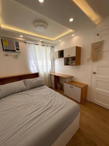 a bedroom with a white bed and a desk at Casa Lucilla in Davao City