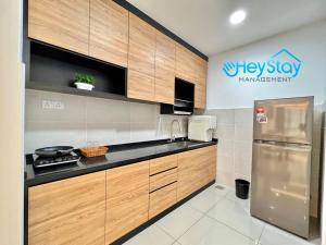 a kitchen with wooden cabinets and a stainless steel refrigerator at Bali Residence Melaka By Heystay Management in Melaka