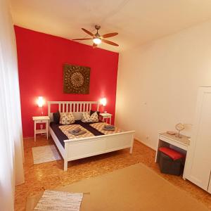 a bedroom with a red wall with a bed and a ceiling fan at Living in the historic Cochem Old Town in Cochem