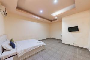 um quarto com uma cama e uma televisão de ecrã plano em Urbanview Hotel Garuda Sky Inn Balikpapan by RedDoorz em Stalkudo