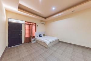 um quarto com uma cama, uma janela e uma porta em Urbanview Hotel Garuda Sky Inn Balikpapan by RedDoorz em Stalkudo