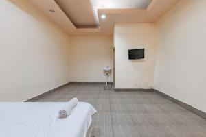 um quarto com uma cama e uma televisão na parede em Urbanview Hotel Garuda Sky Inn Balikpapan by RedDoorz em Stalkudo