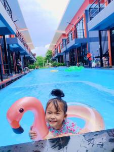 une petite fille dans une piscine avec un cygne rose dans l'établissement The Stories Resort เดอะสตอรี่ส์รีสอร์ต, à Ban Phe