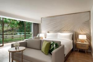 曼谷Mövenpick Hotel Bangkok Ploenchit BDMS的一间带床、沙发和窗户的卧室