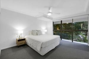 a white bedroom with a bed and a large window at Gemini Court - Hosted by Burleigh Letting in Gold Coast