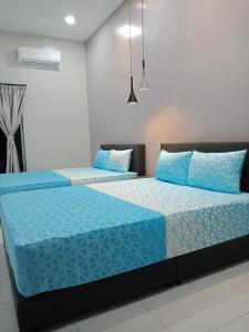 two beds in a room with blue pillows at 61 Homestay in Sitiawan
