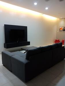sala de estar con sofá y TV de pantalla plana en 61 Homestay en Sitiawan