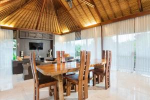a dining room with a wooden table and chairs at Khayangan Kemenuh Villas by Premier Hospitality Asia in Sukawati