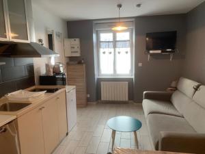 a kitchen and living room with a couch and a table at Studio Mont-Dore, 1 pièce, 2 personnes - FR-1-415-108 in Le Mont-Dore