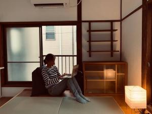 a woman sitting on a couch with a laptop at Bird Place log Tokyo #KS1 in Tokyo