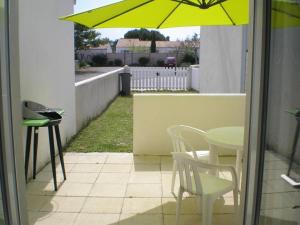 eine Terrasse mit einem Tisch und einem gelben Sonnenschirm in der Unterkunft Maison 2 pièces avec WiFi, Dolus-d'Oléron - FR-1-246A-350 in Dolus d'Oléron + 4 Fotos