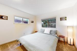 a white bedroom with a bed and two windows at Woodlawn Escape in Seattle
