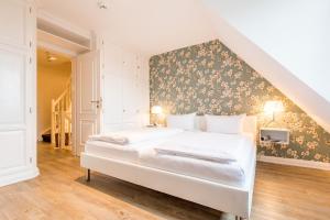 a bedroom with a white bed with a floral accent wall at Haus Ameland, App 3 in Wenningstedt