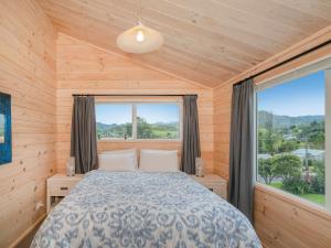 a bedroom with a bed and a large window at Ocean Beach Beauty - Tairua Holiday Home in Tairua