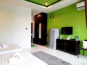 a green room with a refrigerator and a tv at Purimas Resortel in Rawai Beach