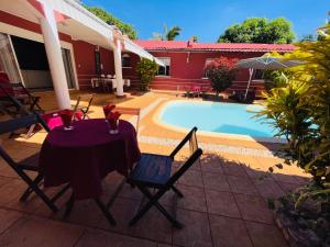 uma mesa e cadeiras sentadas ao lado de uma piscina em Régina Lodge Diégo Suarez Madagascar em Diego Suarez